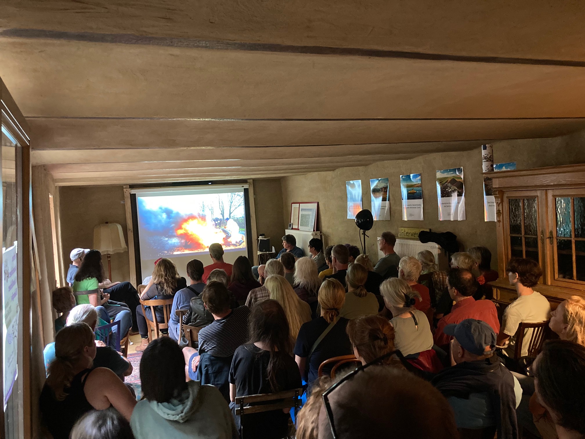 Viele Gäste im Cafe Nr 5, Menschen schauen gebannt bei einer Filmvorführung zu